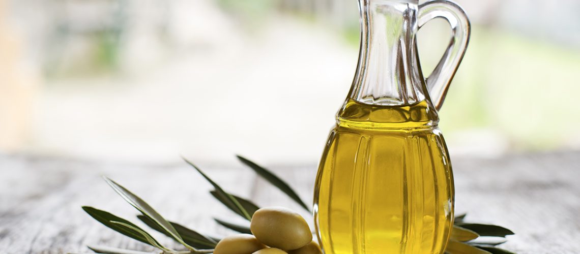 Olive oil and olive branch on the wooden table outside