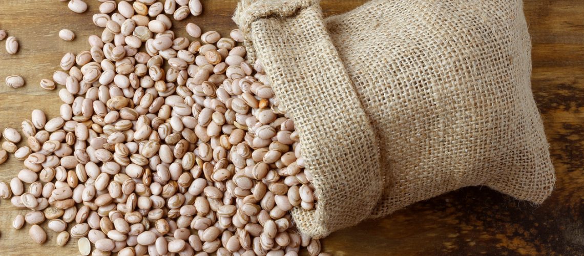 Raw carioca beans in rustic fabric bag. Product name in Brazilian Portuguese. Top view